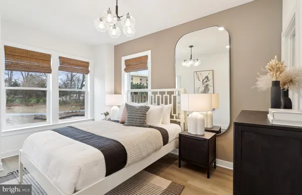 a bedroom with bed a table and windows