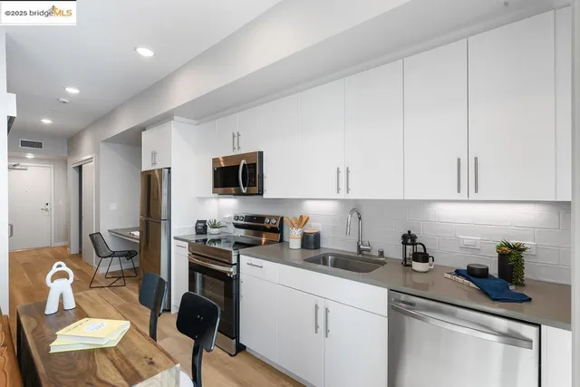 a kitchen with stainless steel appliances granite countertop a refrigerator a stove a sink dishwasher and white cabinets with wooden floor