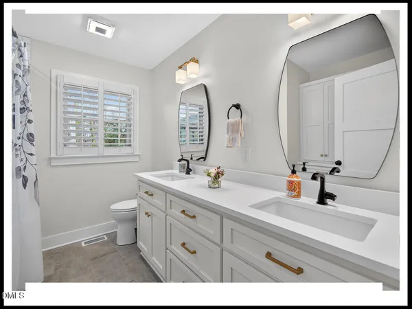 a bathroom with a double vanity sink mirror and toilet