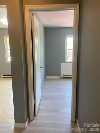 a view of a hallway with wooden floor and a living room