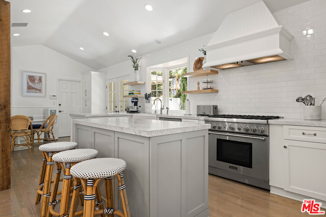 3404 Merrimac Road Los Angeles, CA 90049 - Photo 11 of 29 a kitchen with stainless steel appliances granite countertop a stove and white cabinets