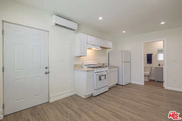 a kitchen with granite countertop a refrigerator and a stove top oven