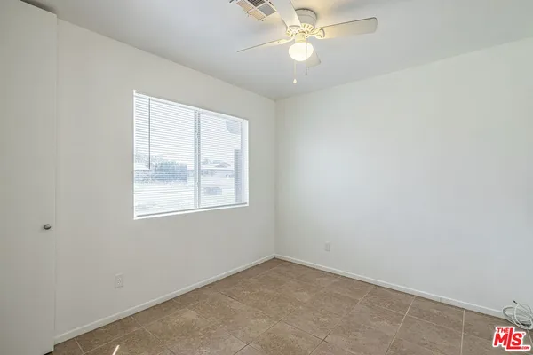 an empty room with a window and a fan