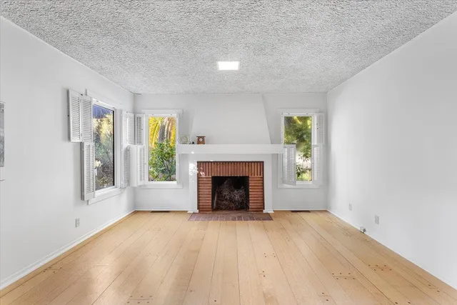 an empty room with windows and fireplace