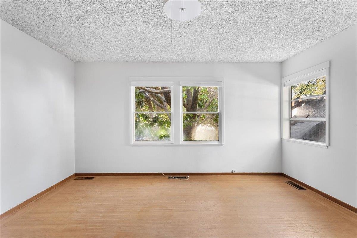 2702 Dana Street Berkeley, CA 94705 - Photo 19 of 37 Empty room with light wood finished floors, plenty of natural light, and a textured ceiling