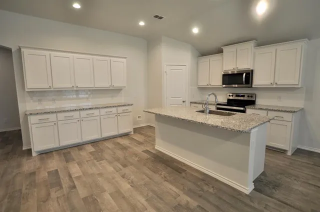 a kitchen with stainless steel appliances granite countertop a stove a sink and a microwave