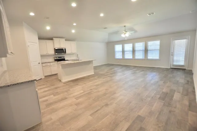 a view of kitchen with kitchen island a sink wooden floor and a refrigerator