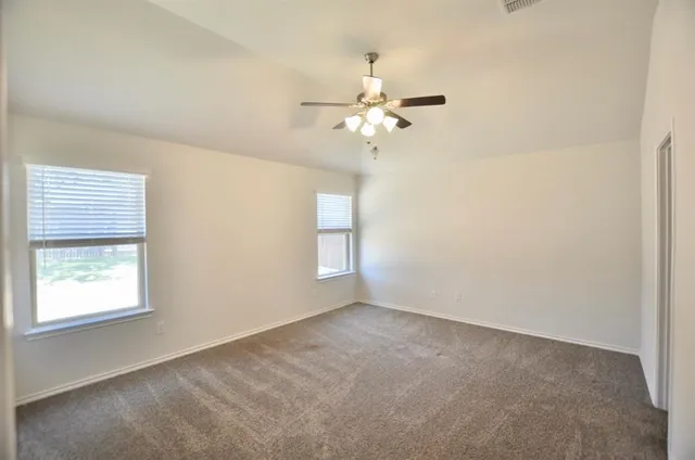 an empty room with windows and fan