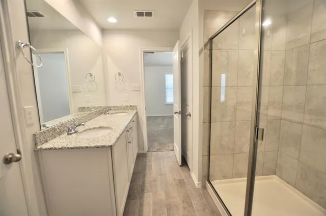 a bathroom with a granite countertop sink a mirror and shower