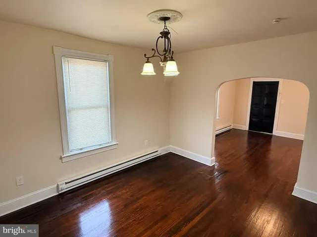 an empty room with wooden floor cabinet and windows