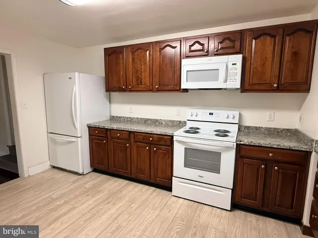a kitchen with granite countertop wooden cabinets and white appliances