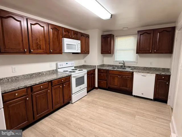 a kitchen with stainless steel appliances granite countertop wooden cabinets a sink and dishwasher a stove top oven