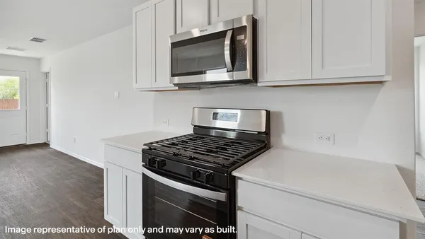 a kitchen with stainless steel appliances granite countertop white cabinets and a stove top oven