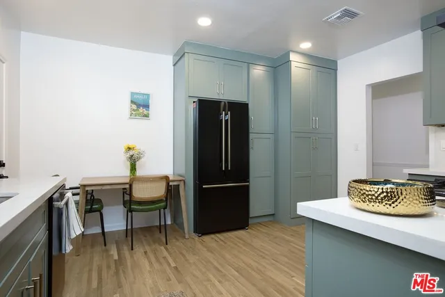 a kitchen with stainless steel appliances wooden floor and a refrigerator