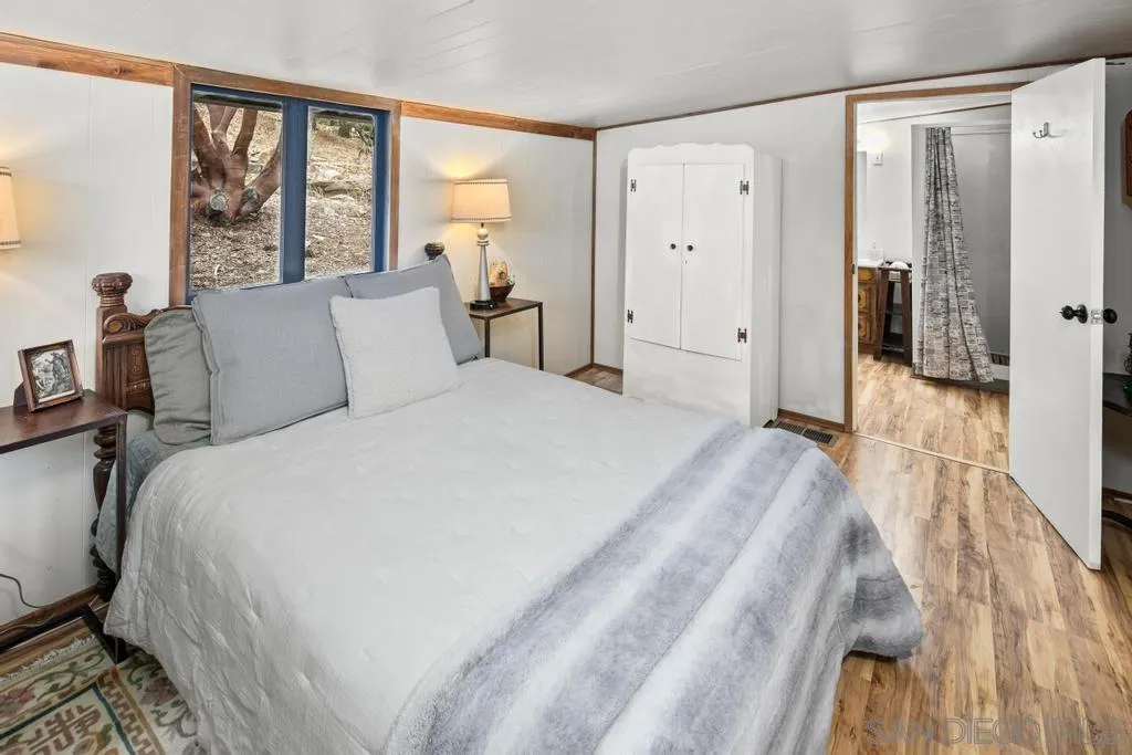 813 Pine Cone Drive Julian, CA 92036 - Photo 15 of 39 a spacious bedroom with a bed and a large mirror next to a window