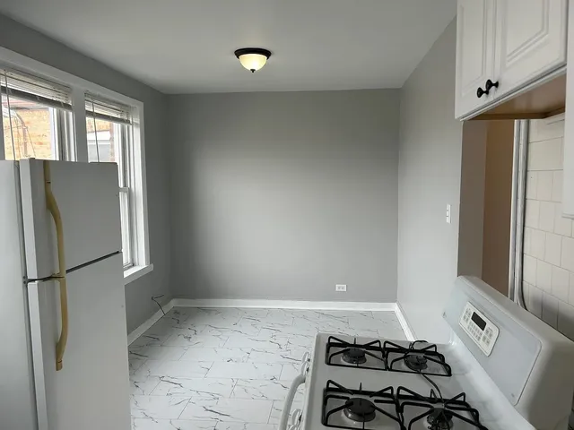 a view of a refrigerator in kitchen and an empty room