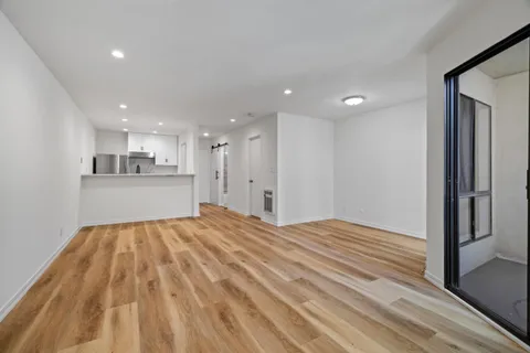 a view of a kitchen with kitchen island wooden floor center island and stainless steel appliances