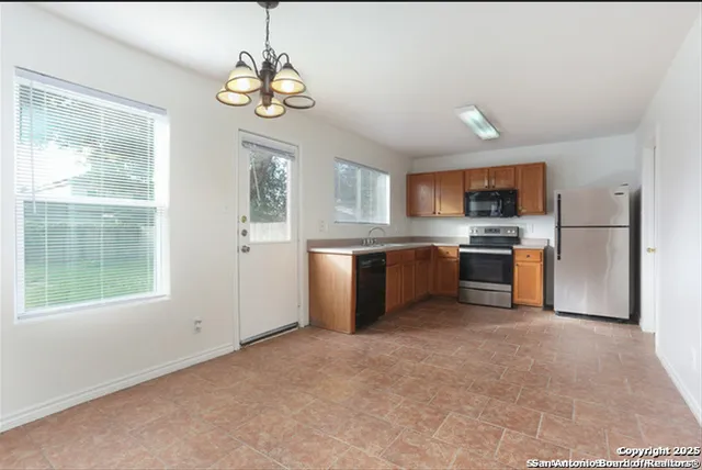 a kitchen with a refrigerator a stove top oven a sink and a window