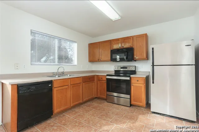 a kitchen with granite countertop a refrigerator stove top oven and sink
