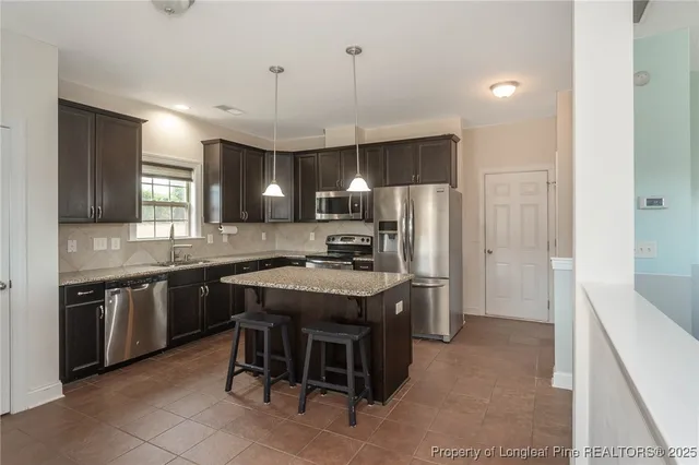 a kitchen with kitchen island granite countertop wooden cabinets and refrigerator