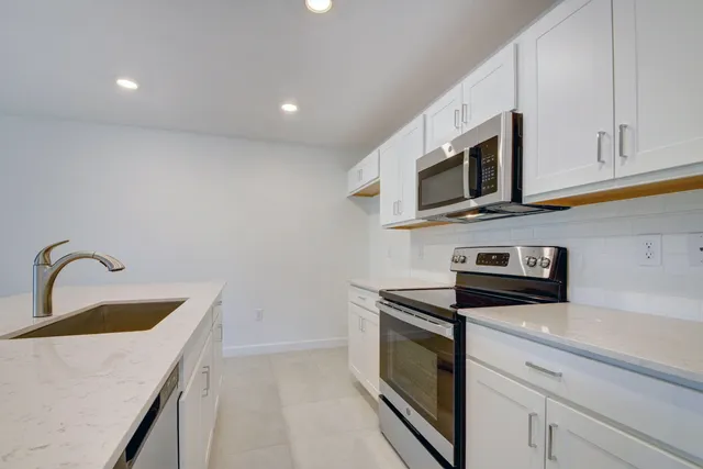 a kitchen with stainless steel appliances granite countertop a sink a stove microwave and refrigerator