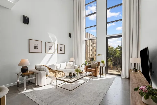 a living room with furniture a flat screen tv and a floor to ceiling window