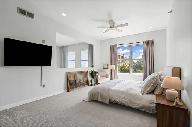 a bedroom with a bed and a flat tv screen on dresser