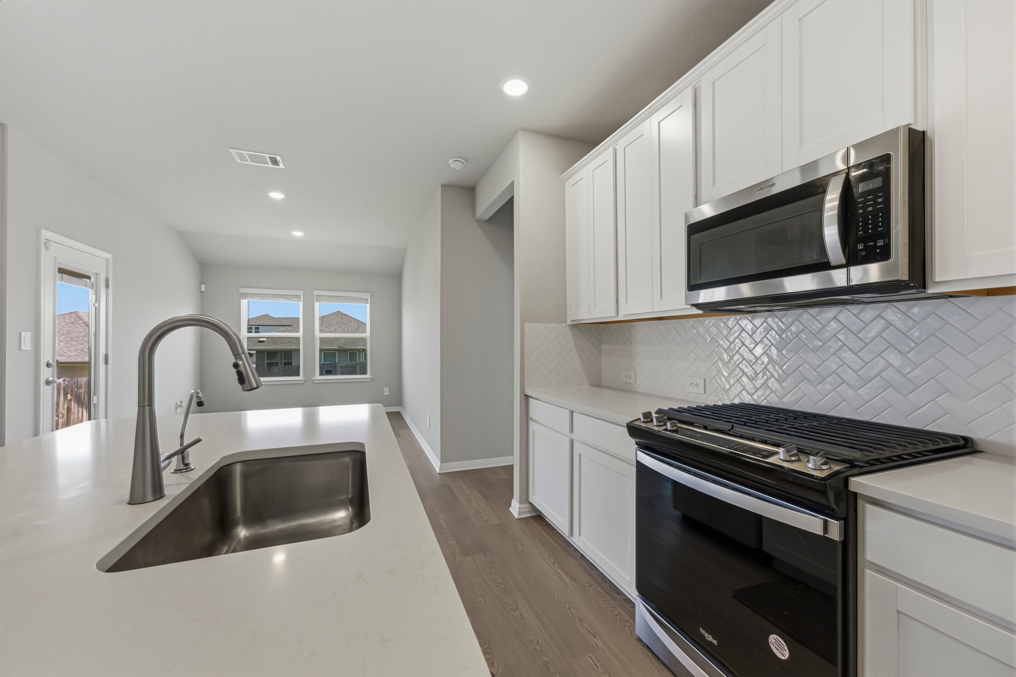 12309 Dairywork Road Buda, TX 78610 - Photo 8 of 29 Kitchen with stainless steel appliances, white cabinets, recessed lighting, wood finished floors, and decorative backsplash