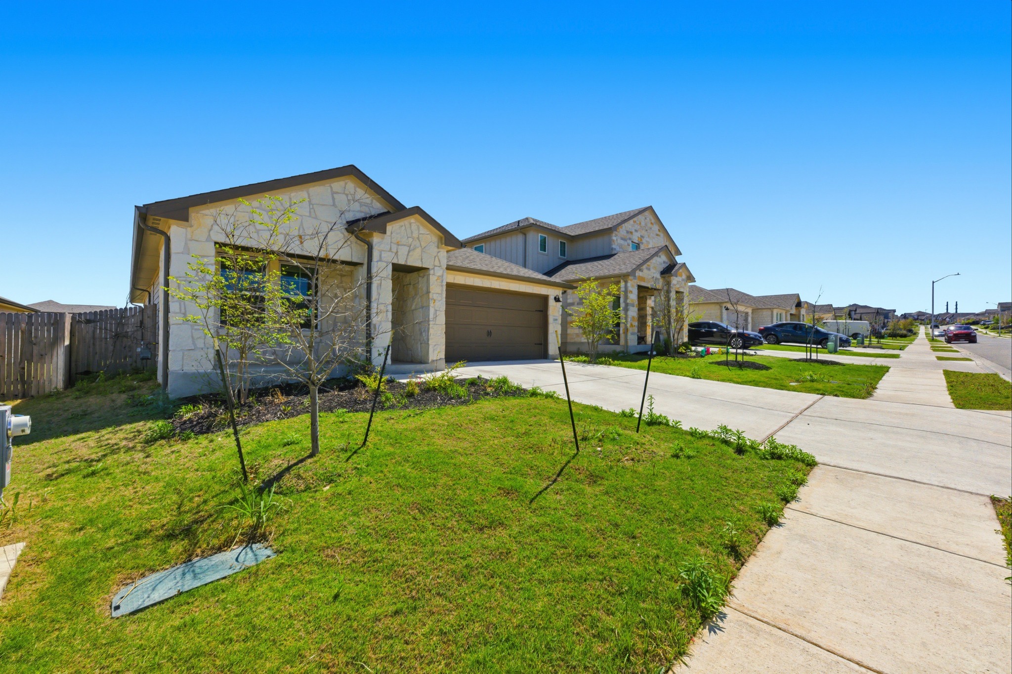 12309 Dairywork Road Buda, TX 78610 - Photo 2 of 29 View of front of home with driveway, an attached garage, stone siding, and a residential view