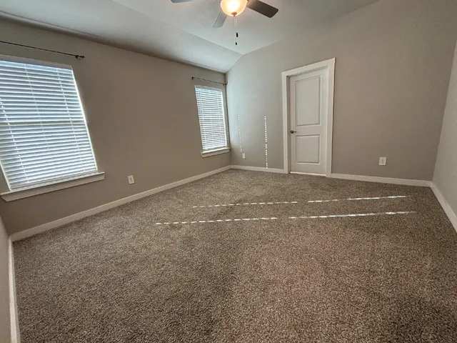 en empty room with windows and chandelier fan