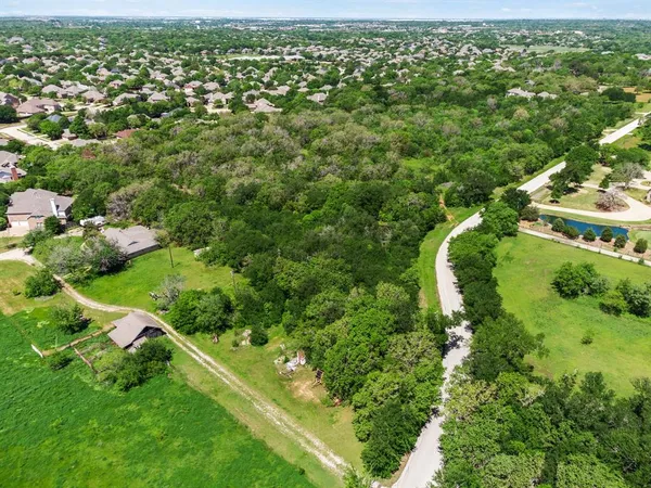 an aerial view of residential houses with outdoor space and trees