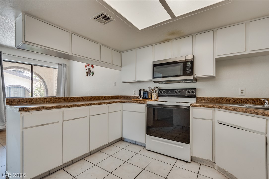5829 Smoke Ranch Road, Unit D Las Vegas, NV 89108 - Photo 20 of 27 White cabinetry paired with durable tile flooring creates a highly functional culinary space.