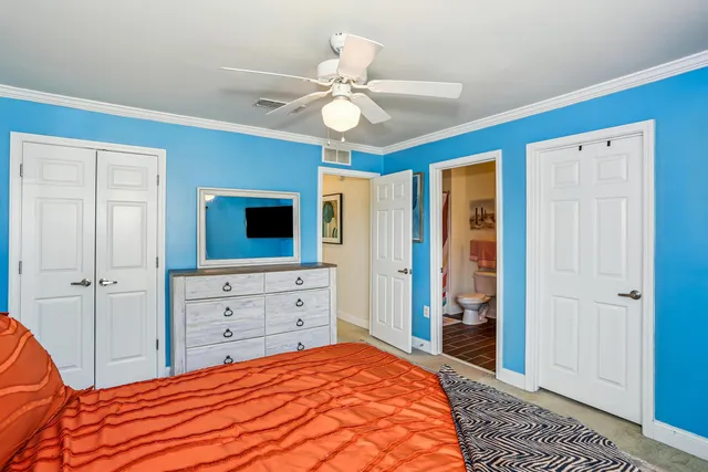 a bedroom with a large bed a chandelier and a dresser