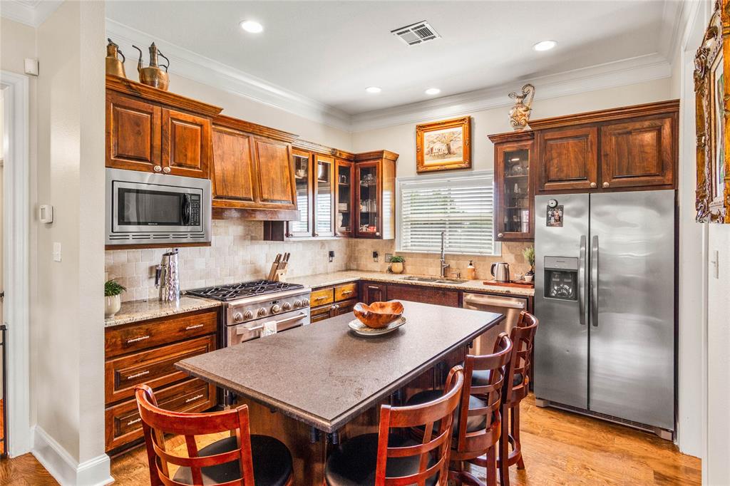 40 Enclave Court Waco, TX 76708 - Photo 8 of 40 a kitchen with stainless steel appliances granite countertop a refrigerator a stove a sink a dining table and chairs with wooden floor