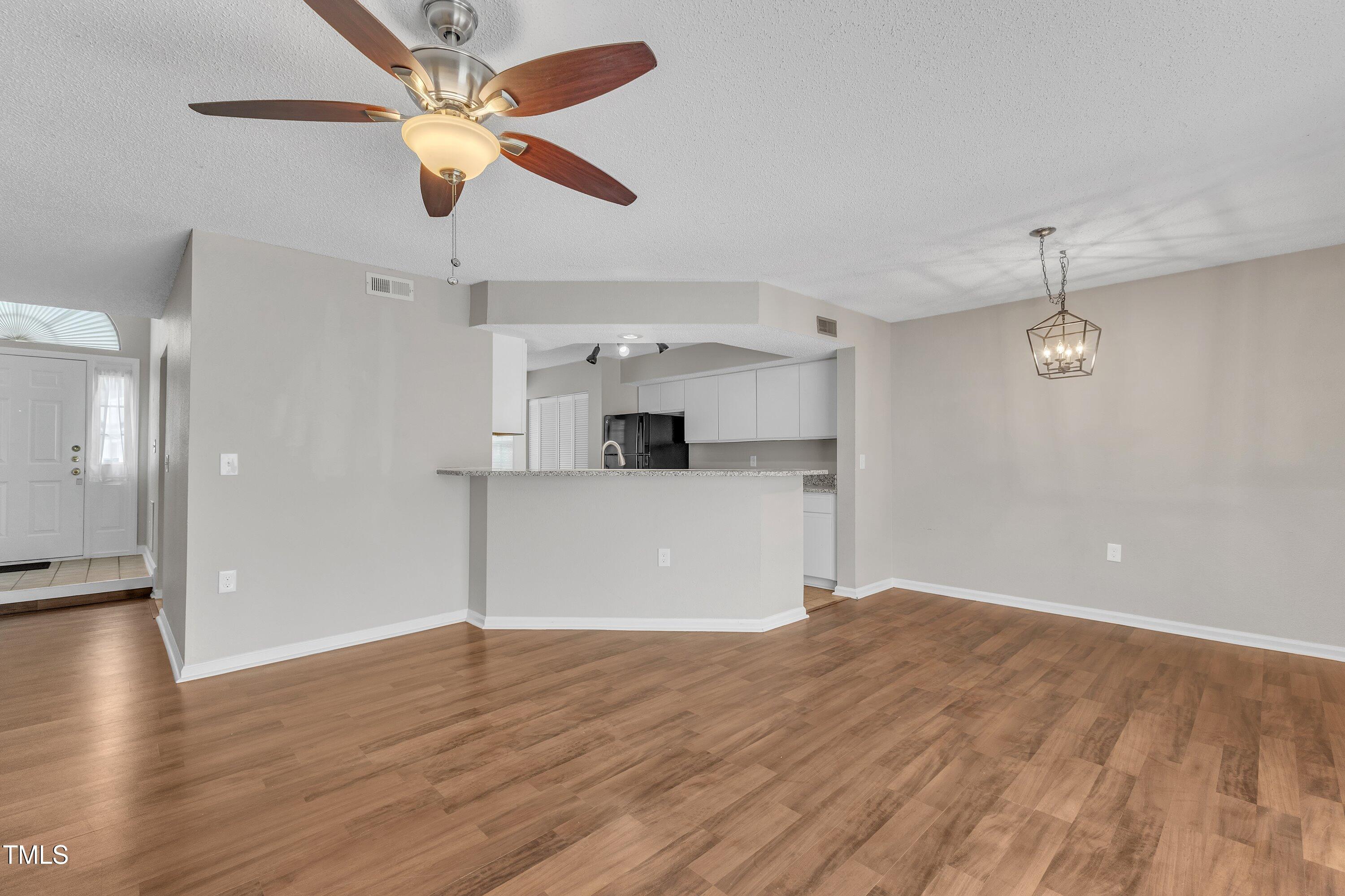 7811 Falcon Rest Circle Raleigh, NC 27615 - Photo 12 of 39 a view of a kitchen with wooden floor and a ceiling fan