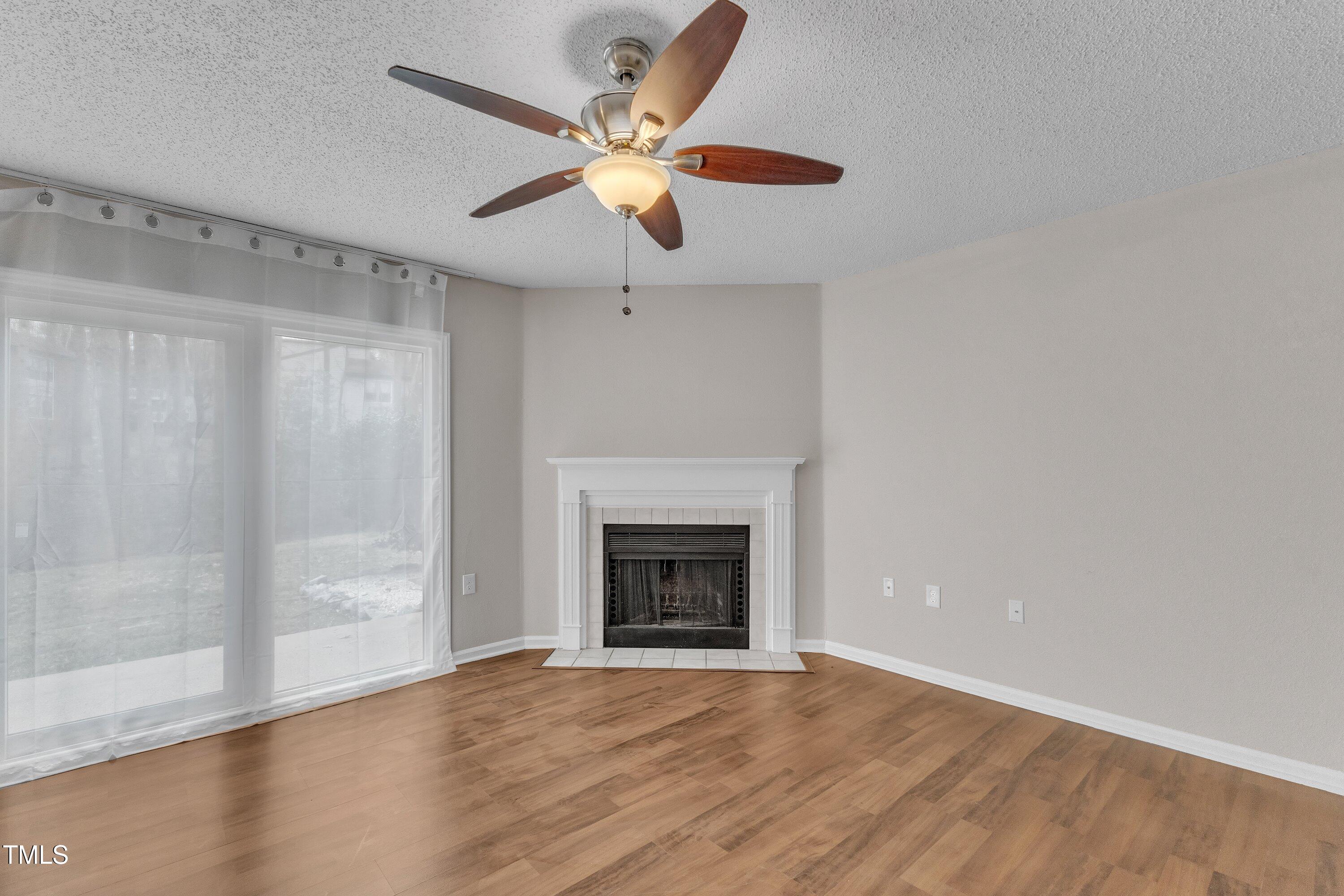7811 Falcon Rest Circle Raleigh, NC 27615 - Photo 9 of 39 a view of an empty room with wooden floor and a fireplace