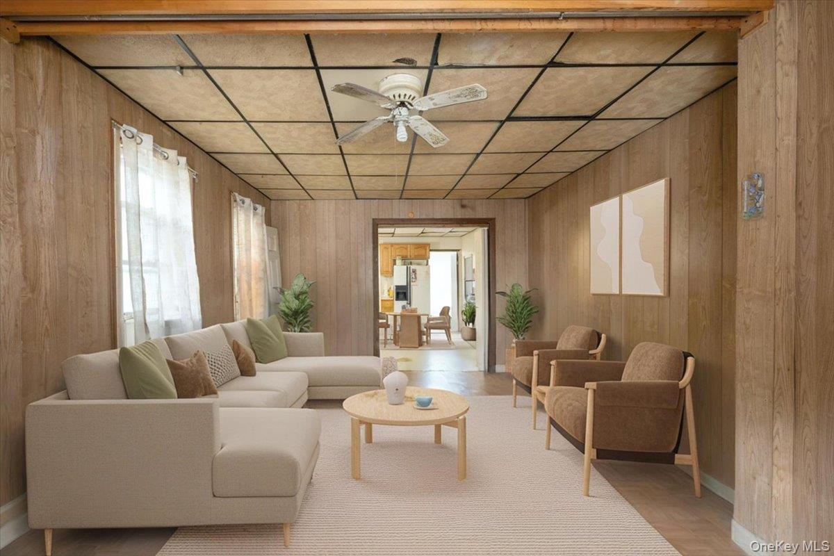 158-24 75th Road Queens, NY 11366 - Photo 2 of 15 Living room with plenty of natural light, wooden walls, ceiling fan, and a drop ceiling