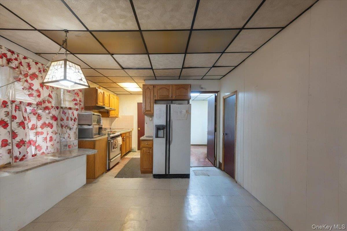 158-24 75th Road Queens, NY 11366 - Photo 3 of 15 Kitchen featuring appliances with stainless steel finishes, light floors, a drop ceiling, light countertops, and pendant lighting