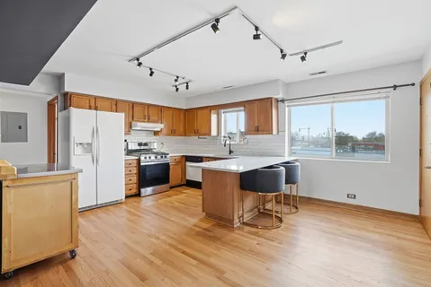 a large kitchen with stainless steel appliances granite countertop a sink and wooden cabinets