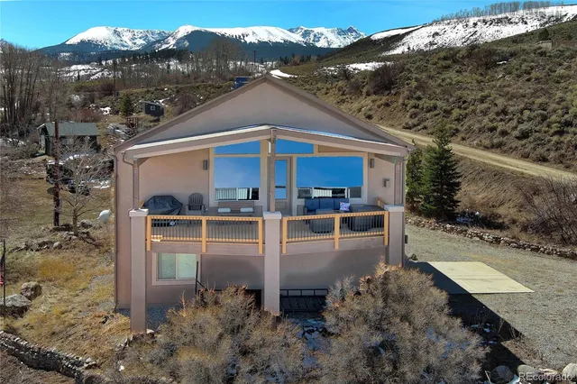 a view of a white house with a yard plants and large tree