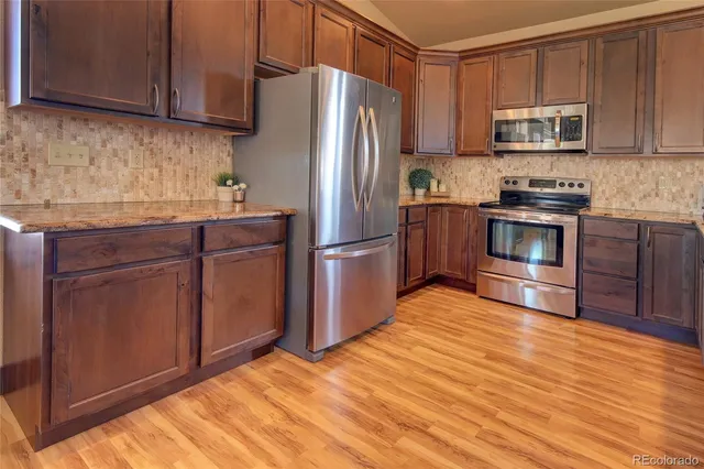 a kitchen with granite countertop wooden floors stainless steel appliances and a sink