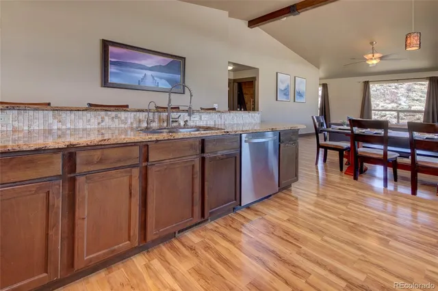 a open kitchen with kitchen island granite countertop wooden cabinets a sink and dishwasher