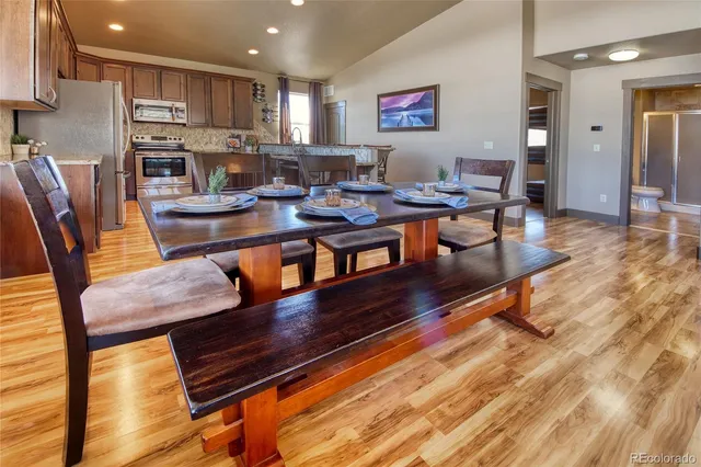 a living room with stainless steel appliances dining table chairs and a kitchen view