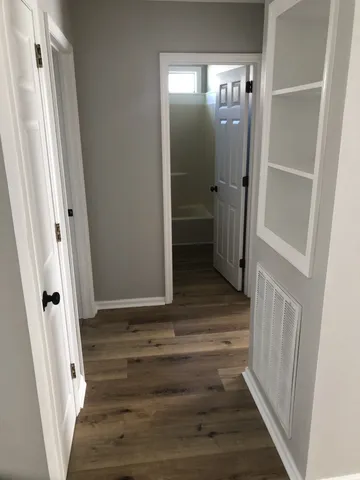 a view of an empty room with wooden floor and a window