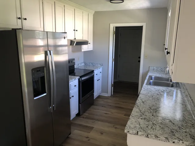 a kitchen with granite countertop a stove and a refrigerator
