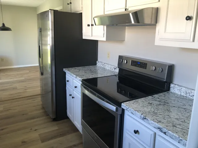 a kitchen with stainless steel appliances granite countertop a refrigerator and a stove