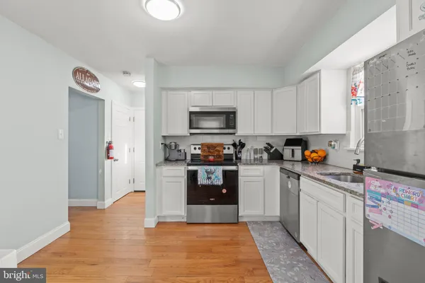a kitchen with refrigerator and wooden floor