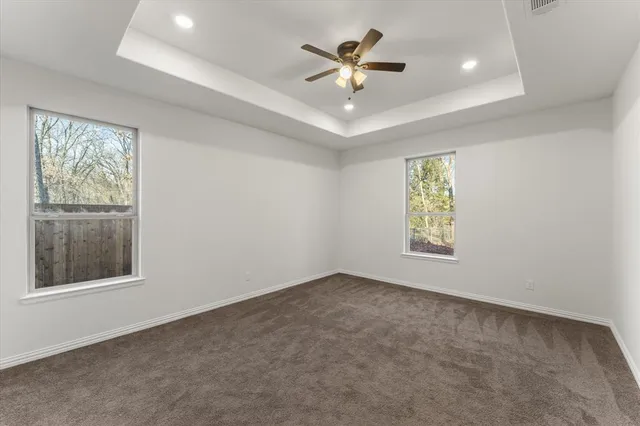 an empty room with windows and ceiling fan