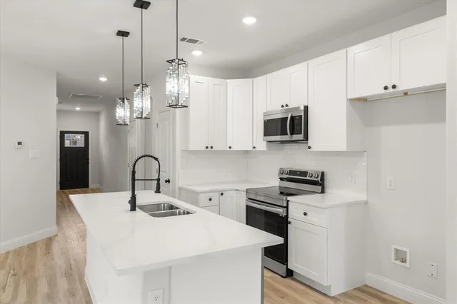 a kitchen with stainless steel appliances a sink a stove a refrigerator and cabinets