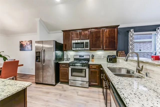 a kitchen with stainless steel appliances granite countertop a sink stove and refrigerator